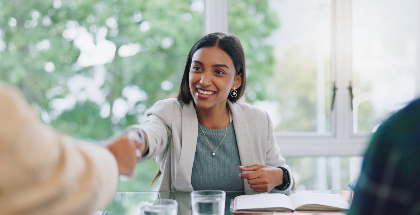 Een professional begroet haar gesprekspartner tijdens een sollicitatiegesprek